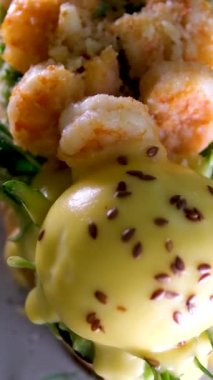 Lezzetli karides karidesli Benedict peynirli avokado ve yumurtalı tost. Parmesan yeşili iştah açıcı aromatik öğle yemeği aperatifi. Gri tabakta keten taneleri serpiştirilmiş. Restoran servisi