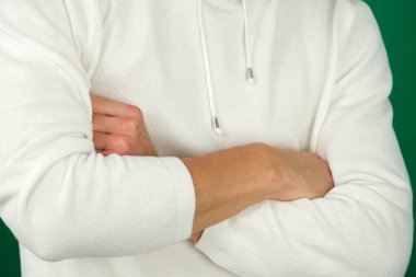 Kollarını çapraz yapmış çekici genç bir adamın portresi yeşil arka plandaki yakışıklı bir adamın yeşil arka plan duygularında izole edilmiş yakın plan kromakey genç adam. beyaz kazak