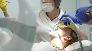 Genç kadın dişçi. Ortodontiste resepsiyon. Diş tellerinin değiştirilmesi. Cilalıyorum. Jel yapıştırma. Yüksek kalite 4k görüntü