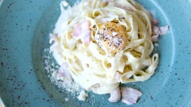 Parmesan peynirli makarna, ahşap arka planda yalıtılmış kil tabakta. Ev yapımı Carbonara makarnası.