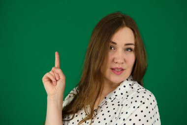 Genç, şişman, güzel bir kadının stüdyo çekimi. Mutlu yüzle gülümseyen güzel bir kadın. Ayrı bir şekilde yan tarafa bakıyor ve işaret ediyor. 