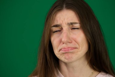 Yeşil arka plandaki genç bir kızın farklı duyguları ağlar güzel yüz hatları gerçek insanlar pembe tişörtlü beyaz tenli. Avrupa