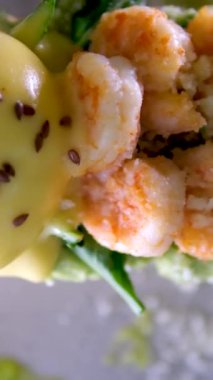 Lezzetli karides karidesli Benedict peynirli avokado ve yumurtalı tost. Parmesan yeşili iştah açıcı aromatik öğle yemeği aperatifi. Gri tabakta keten taneleri serpiştirilmiş. Restoran servisi