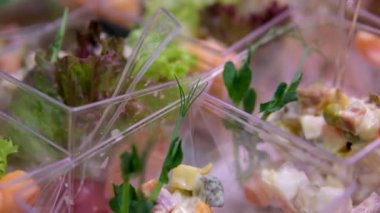 Marul yaprağı mayonez peynirinin üzerindeki açık büfe masasında plastik tabakta porsiyon salatalar. Kutlamada lezzetli yemeklerin güzel sunumu