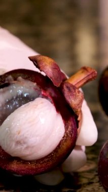 Beyaz eldivenli kadın eli, Asya Tayland 'daki bir restoranın içinde ne olduğunu göstermek için mor bir tropikal meyve mangosinesini çevirir. 