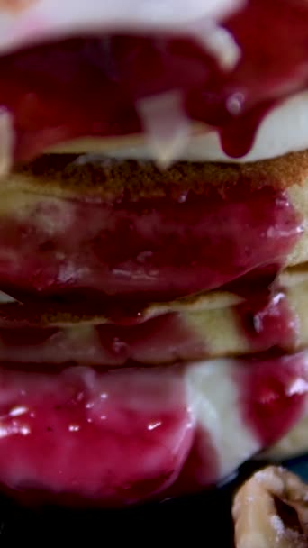 ココナッツフレークブルーベリーヘーゼルナッツアーアーモンドフレークラズベリーとサワークリームで美味しい朝食で飾られたケーキの形で ブループレートでおいしいパンケーキのスタック フォークで食べる — ストック動画
