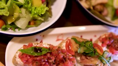 Kırmızı balıklı sandviçler, domates ve roka diğer tabakta domatesli Sezar salatası, marul ve peynir sarı kaşık beyaz. Restoranda servis edilen tabaklar.