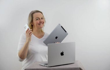 Kadın, Apple 'dan hediye olarak çeşitli aletler iPad Macbook iPhone 13 Pro Max' ten beyaz arka planda orta yaşlı sarışın dans eden yeni metin teknolojileri için yer açmaktan mutluluk duyuyor.