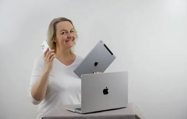 Appleの様々なガジェットから贈り物として受け取った女性IpadのMacbook Iphone Pro Max白い背景に中年のブロンドのダンス喜びテキストのためのスペースを振って最新の技術の幸福が勝利を獲得 ストックフォト
