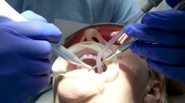 Diş kliniğinde koruyucu maskeli iki doktor hasta kıza hizmet ediyor. İş Dişçiliği. Sağlık ve tıp konsepti. Yüksek kalite 4k görüntü