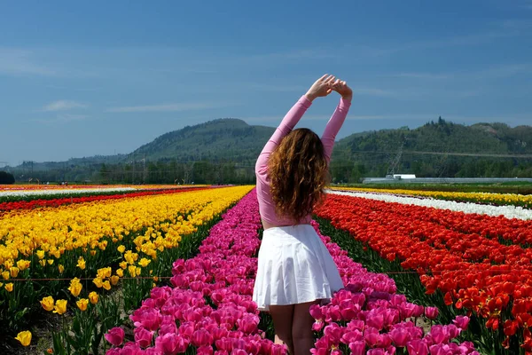 Happy woman on blooming field of tulips. High quality photo