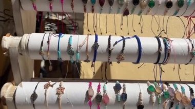 Yunanistan 'ın Korfu adasındaki beyaz stantlara takılan kolyeler ve bilezikler taşlardan ve dokuma ipliklerden yapılan güzel el yapımı çantaları satın alıyor. Bilezikler ve el sanatları satıldı.