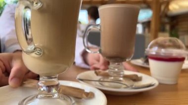 Masada iki bardak sıcak içecek kakao ve latte karşılaştırması ile birlikte beyaz tabakta yer değiştiren tatlı kız plastik kap jöle restoranının yanında servis ediliyor. kafe