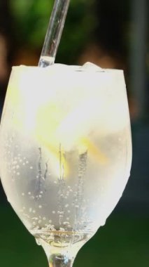 Buzlu limonatayı bardağa dök, soda koy, limonu kamışla karıştır, sokağın ortasında soğuk bir içecek videosu çek, köpüklü köpüklerle doldur. yakın plan