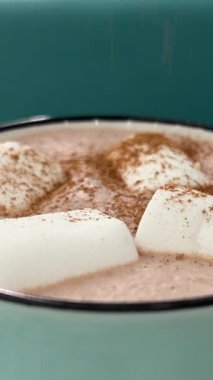 Tarçınlı yeşil fincanla serpiştirilmiş marşmelovlu kakao. Gök mavisi arka plan lezzetli sıcak kakao seramik bardakta şekerlemeler ve kışlık şeylerle çevrili. Sıcak tatil ve yeni yıl kavramı.