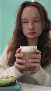 Kızların elinde kapuçino latte ile şam fıstığı ve kurutulmuş meyve ahududu bir bardak köpüklü sıcak içecek beyaz bluzu açık yeşil bir turkuazın üzerinde saçları. Gökyüzü