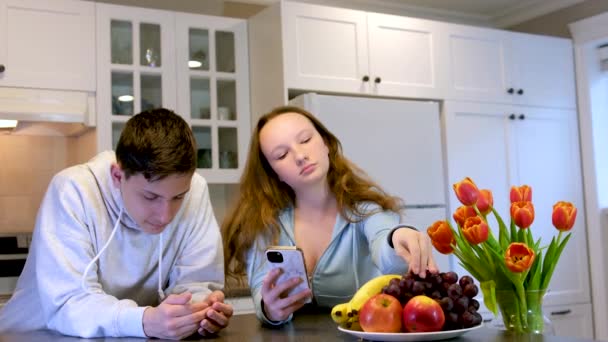 Adolescentes Cozinha Comendo Frutas Jogando Telefone Bela Mobília Branca Casa — Vídeo de Stock