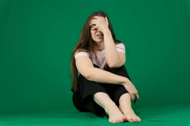 Öfkeyle başını sallayan ve yeşil arka planda ağlayan genç bir bayan. Orta boy. Yüksek kalite fotoğraf