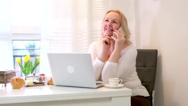Średnim Wieku Dorosła Kobieta Pracuje Przy Komputerze Rozmawiając Przez Telefon — Wideo stockowe
