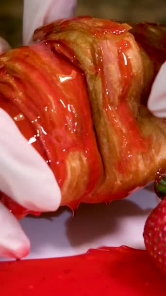 Mãos Enluvadas Estão Quebrando Delicioso Croissant Fresco Encharcado Xarope Vermelho — Vídeo de Stock