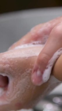 El bakımı. Ellerini Akan Su Altında Yıka. Okulun lavabosunda ellerini sabunla yıkayan bir kadın. Coronavirus COVID 19 'un Corona virüsünü önlemek için ellerini sabun ve suyla yıkamasını önle