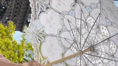 a cheerful teen girl stands against the backdrop of the Eiffel Tower she raised her hand, you can advertise a travel agency trip to Paris France. girls in the hands of an openwork umbrella