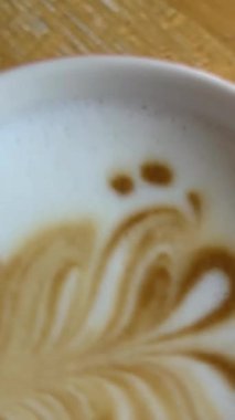 Ahşap sehpanın üzerinde kırmızı bardakta Latte sanatı. Sıcak kahveli latte. Yakın çekim. Yüksek kalite 4k görüntü