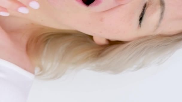 スローモーション季節のアレルギー冷たい乾燥した空気クローズアップ女性スニーズカバー彼女の手上の白い背景に水っぽい目なめる唇不快な感覚 — ストック動画