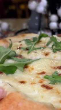 Geleneksel italyan pizzasında stracciattella peynirli yeni pişmiş pizzaya pesto sosu döken şefin yakın çekimi. Dört peynirli, roka ve mozzarella peynirli pizza.