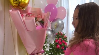 15. yaş gününü kutluyoruz. Genç kız odada koşup helyum balonları çekiyor.