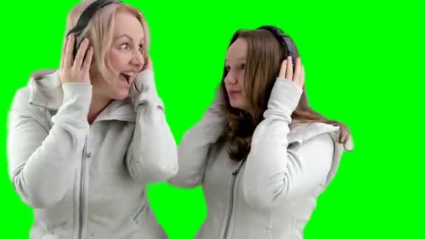 同じスポーツの母親と娘は ヘッドフォンの白い背景に灰色の色を着て 音楽を聞き 互いに笑顔になる 軽いヨーロッパの女性が一緒に歌う — ストック動画