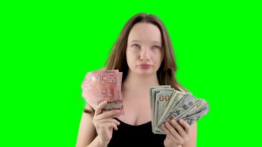Kanada doları ve Amerikan doları arasında seçim yapmak kız elinde beş paket Kanada doları ve dudak büken büyük 100 dolarlık banknotlarla çok para seçer. yolculuk hediyesi