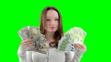 İki büyük deste yeni banknotla altın genç kız. 100 dolarlık banknotlar. Beyaz arka planda spor gri bir kazakla 100 euro. Gevşek saçlı, kendine güvenen genç kız. Yeni nesil