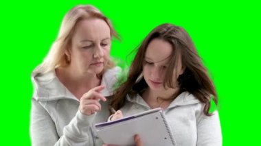 Anne ve kızı matematik problemlerini birlikte çözüyorlar. Ödev yaparken. Not defterine yazan kız, kalem kadınla birlikte parmak uçlarında karşılıklı anlayış gösteriyor. ergenlik