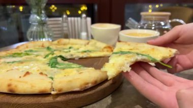 Peynirli ve roka soslu pizza, bir el taze pişmiş lezzetli bir parça çeker. Taze pizza, bir dilim pizza ve süper esnek peynir. Yüksek kalite 4k görüntü