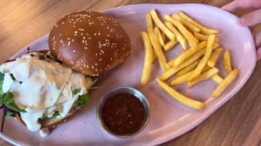 Restoran masasında domuz pastırması ve peynirli sığır burger yakın plan. Lezzetli Amerikan yemekleri. Restoranda servis edilen kızarmış çizburgerle patates kızartması nefis. - Evet. Yüksek kalite