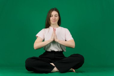 Yeşil arka plan renginde genç bir kızın farklı duyguları güzel yüz hatları gerçek insanların pembe tişörtlü beyaz tenleri. Avrupa Yogası. Genç kız spora gider. Yüksek kalite fotoğraf