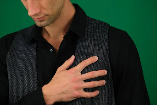 Young Man Holding A Hand To His Heart Due To This Pain emotions of a handsome man guy on a green background chromakey close-up dark hair young man. High quality photo