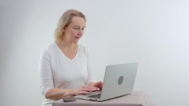 Karantina sırasında evden çalışmak için dizüstü bilgisayara ciddi şekilde odaklanan Coronavirus, sosyal mesafeyi korumak için evde çalışan günlük üniformalı bir kadın..