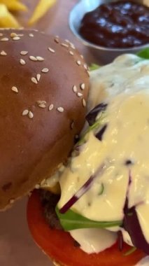 Restoranda fast food burger ve patates kızartması sipariş ettim. Yüksek kalite hamburger ve ahşap masada kızarmış patates.