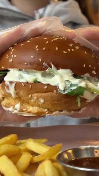 飢えた若い女性がビッグハンバーガーを噛んでいる ファーストフードカフェでハンバーガーを食べる クローズアップ 高品質の4K映像 — ストック動画