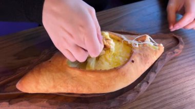 Gürcistan Adjarian Khachapuri Hand 'de suluguni peyniri ve yumurta sarısını karıştıran kişi. Adjarian Khachapuri' nin malzemelerini restoranda çatalla karıştırıyor. Peynirli ve yumurtalı turta. Çok lezzetli.