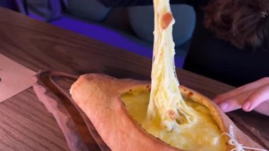 Gürcistan Adjarian Khachapuri Hand 'de suluguni peyniri ve yumurta sarısını karıştıran kişi. Adjarian Khachapuri' nin malzemelerini restoranda çatalla karıştırıyor. Peynirli ve yumurtalı turta. Çok lezzetli.