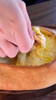 Gürcistan Adjarian Khachapuri Hand 'de suluguni peyniri ve yumurta sarısını karıştıran kişi. Adjarian Khachapuri' nin malzemelerini restoranda çatalla karıştırıyor. Peynirli ve yumurtalı turta. Çok lezzetli.