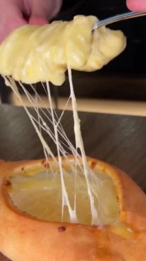 Gürcistan Adjarian Khachapuri Hand 'de suluguni peyniri ve yumurta sarısını karıştıran kişi. Adjarian Khachapuri' nin malzemelerini restoranda çatalla karıştırıyor. Peynirli ve yumurtalı turta. Çok lezzetli.