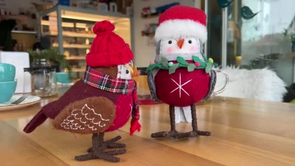 スカーフコンセプト冬の暖かいクリスマスがカフェの子供のおもちゃに暖かい装飾を保つために待っているテーブルの上のホームメイドの布から作られた2つの鳥のブルフィンチ — ストック動画