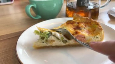 Peynirli tart brokolili ıspanak ve somon peynirli ve bir kafede çatallı, ahşap masa beyaz tabağında, çiçekli, Vasilkov 'un lezzetli öğle yemeği atıştırmalığının yanında. Öğle yemeği