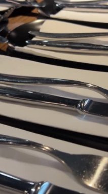 Restorandaki boş bir masada hazırlanmış çatal ve bıçak. Büyük bir şirket çatal bıçak etkinliği için uzun bir masa hazırlığı için beyaz peçetelere çatal ve bıçak servis ediyorlar.