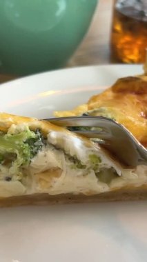 Peynirli tart brokolili ıspanak ve somon peynirli ve bir kafede çatallı, ahşap masa beyaz tabağında, çiçekli, Vasilkov 'un lezzetli öğle yemeği atıştırmalığının yanında. Öğle yemeği