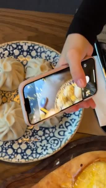 一名女孩在格鲁吉亚一家餐馆为食物拍照 Khachapuri Khinkali用水加柠檬和过道在网志上为社交网络拍照和录像 博客Food — 图库视频影像